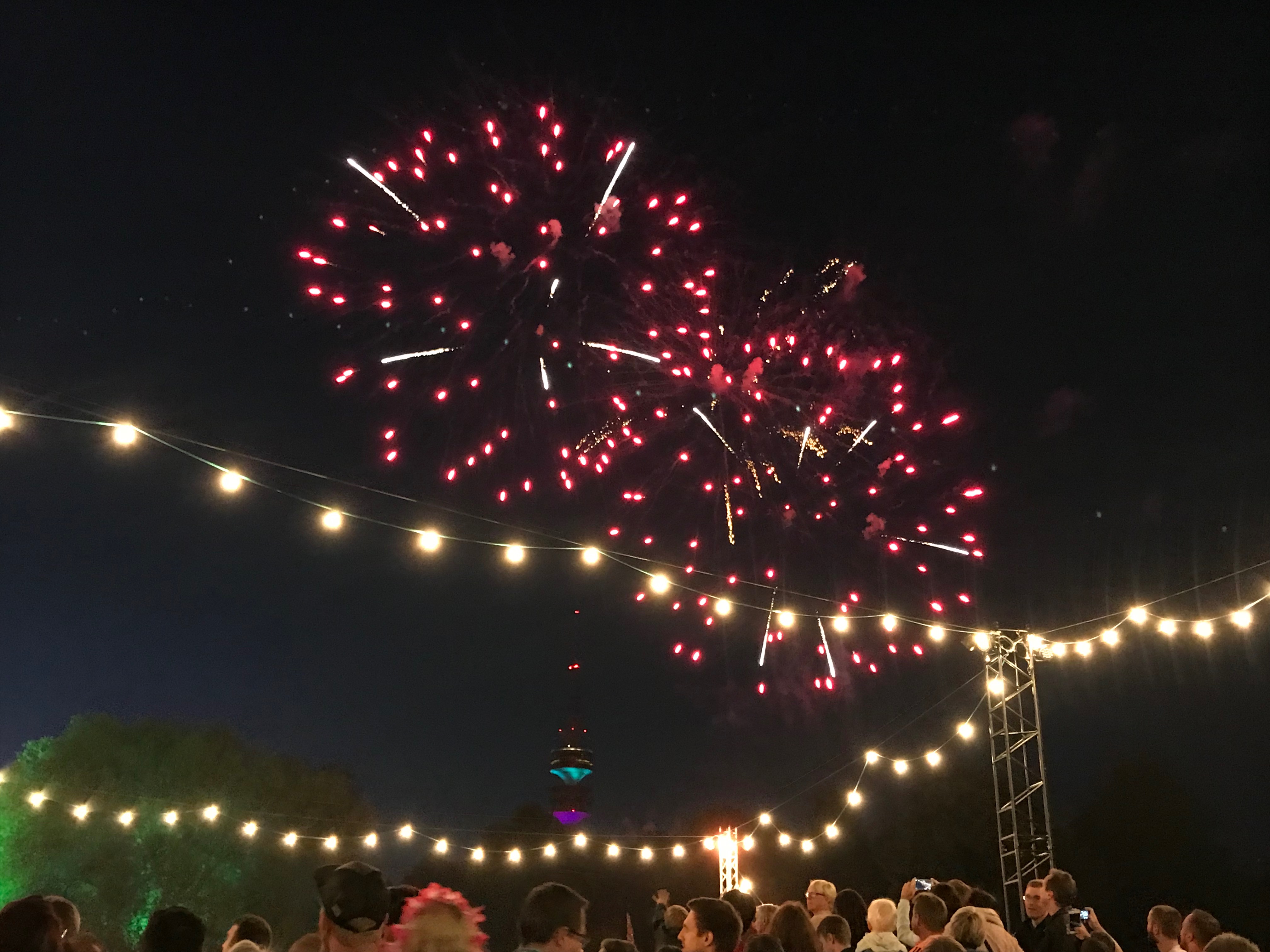 Rotes Feuerwerk über dem Tollwood Festival und im Hintergrund der Olympiaturm